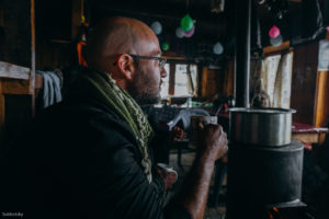 Man sitting lodge fireplace holding cup.