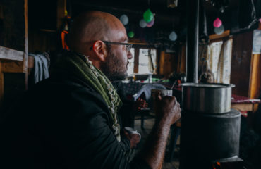 Man sitting lodge fireplace holding cup.