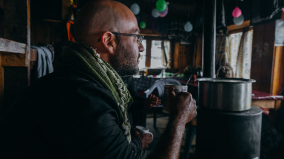 Man sitting lodge fireplace holding cup.